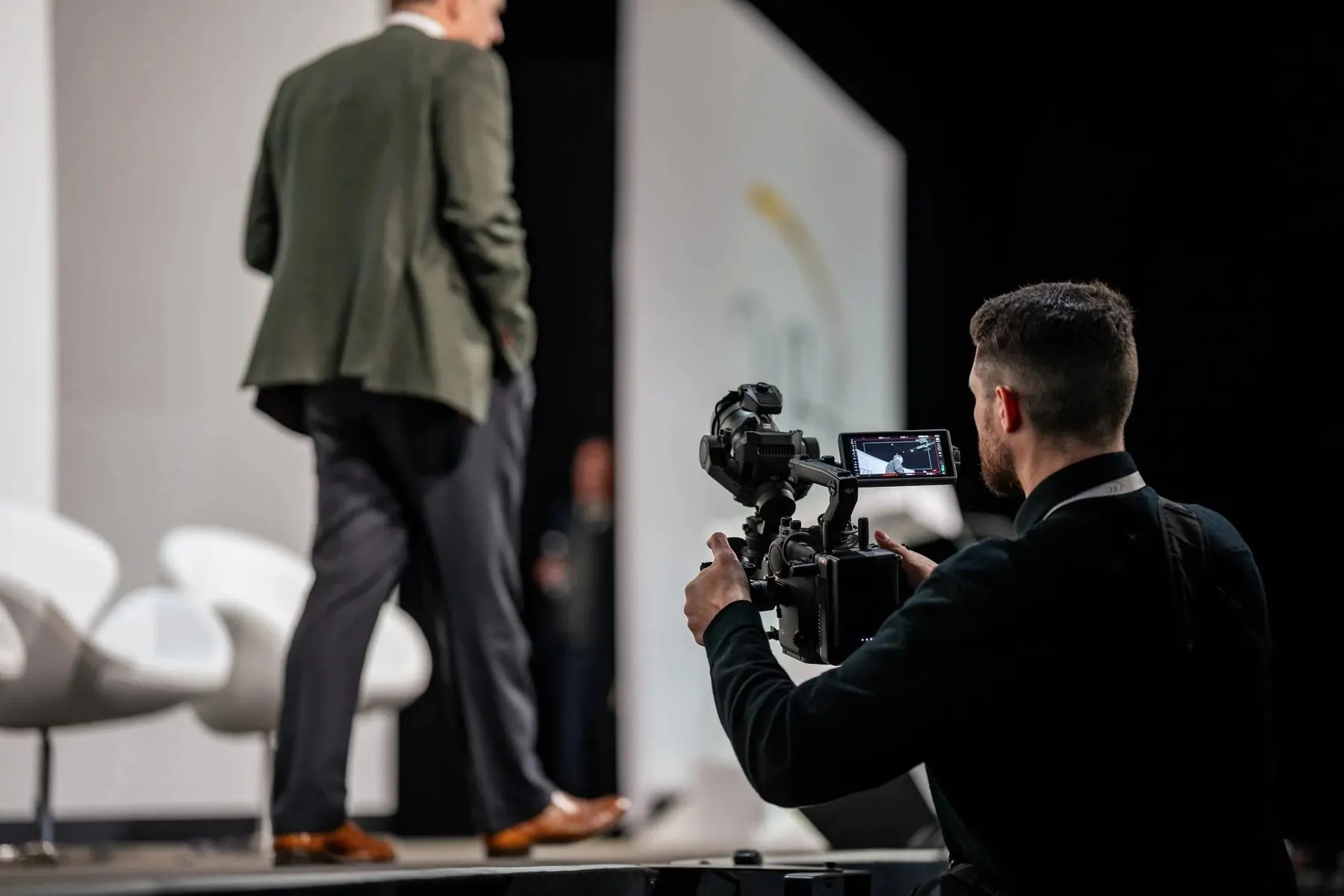 A camera operator filming a speaker on stage